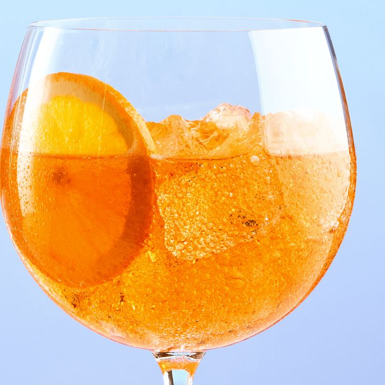 A close up of a glass of Joy Spritz orange flavour, with a slice of orange.