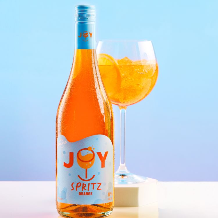 Joy Spritz bottle and glass with an orange to blue gradient background.