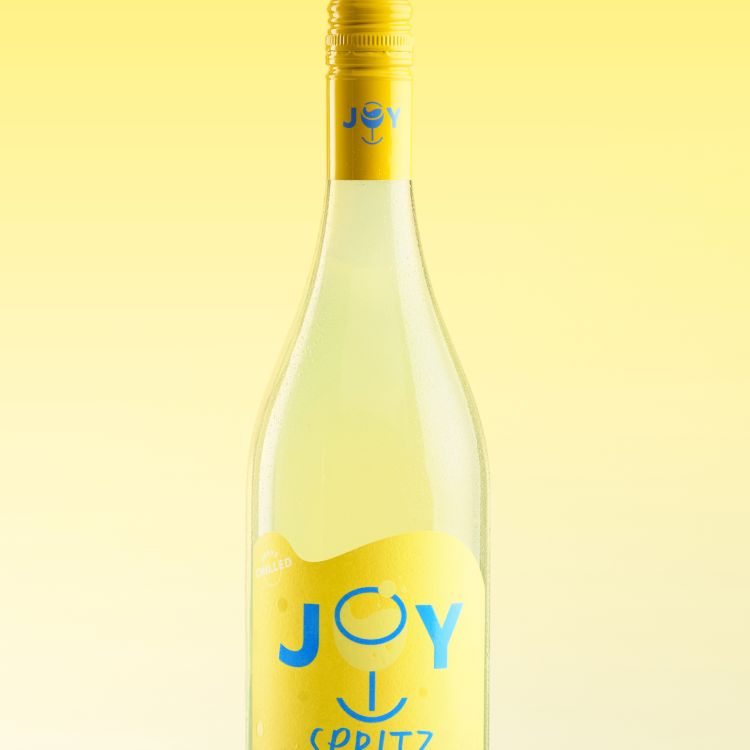 A bottle of Joy Spritz Lemon against a yellow gradient background.